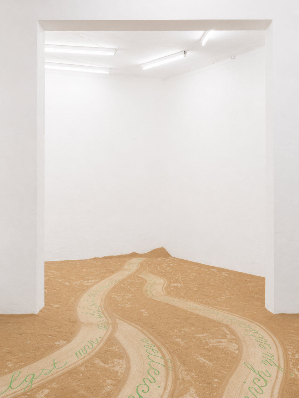 Floor installation made of mealworm frass and green typographic pathways extending through a white exhibition space. The pathways branch and converge, inviting visitors to follow them through the room.